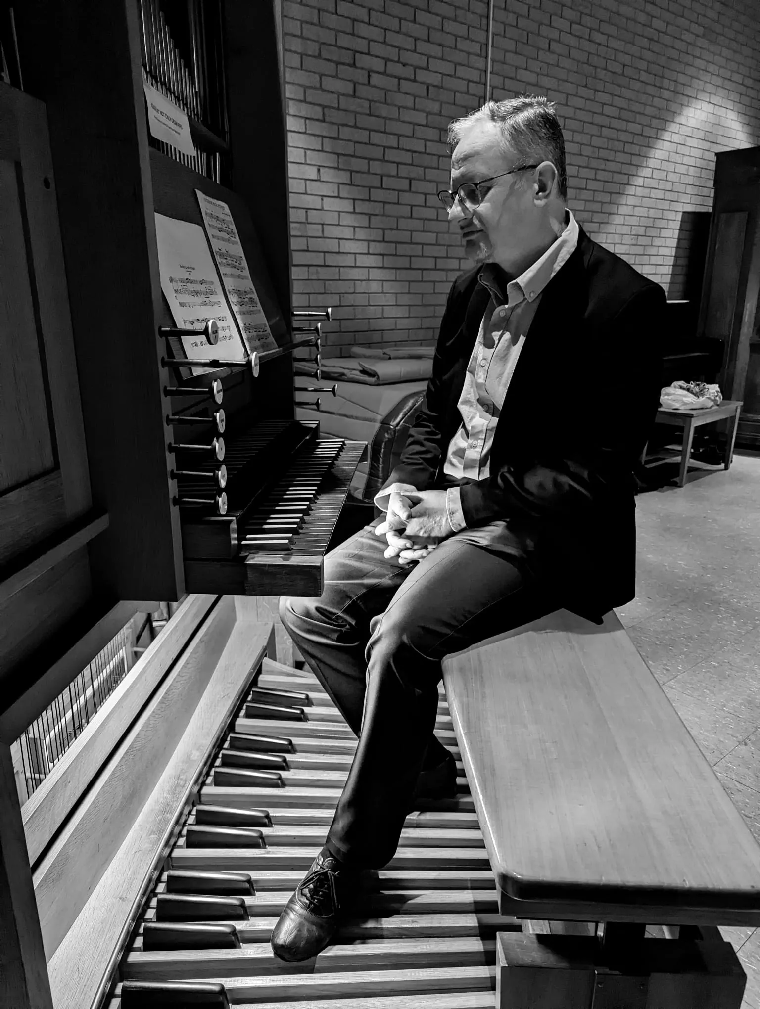 Rudimar Bonamigo in profile at the organ console, feet on the pedalboard