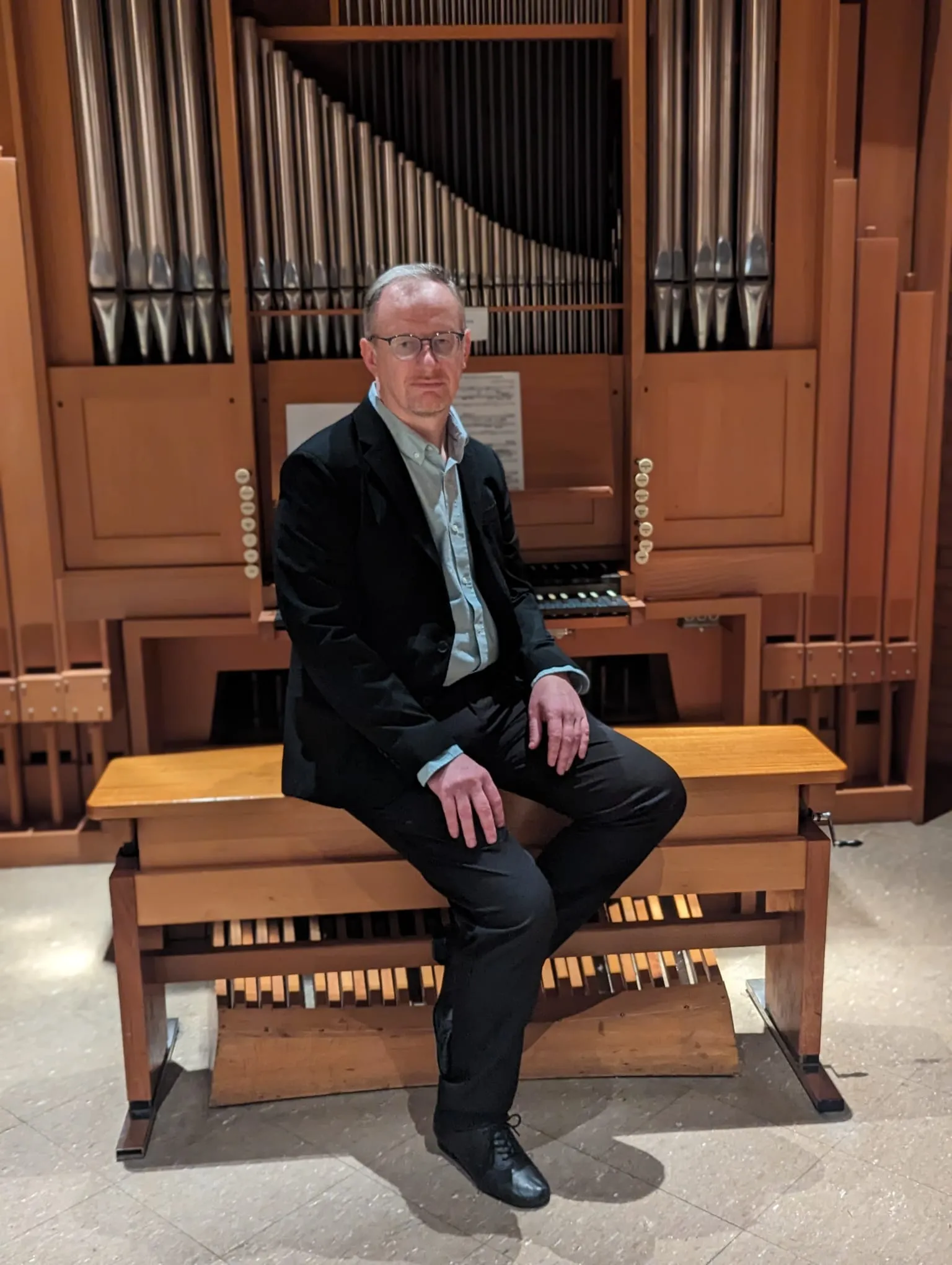 Rudimar Bonamigo seated before a wall of organ pipes